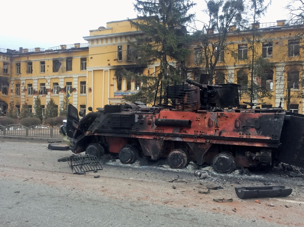 A destroyed Ukrainian armoured personnel carrier vehicle is seen in front of a school which, according to local residents, was on fire after shelling in Kharkiv