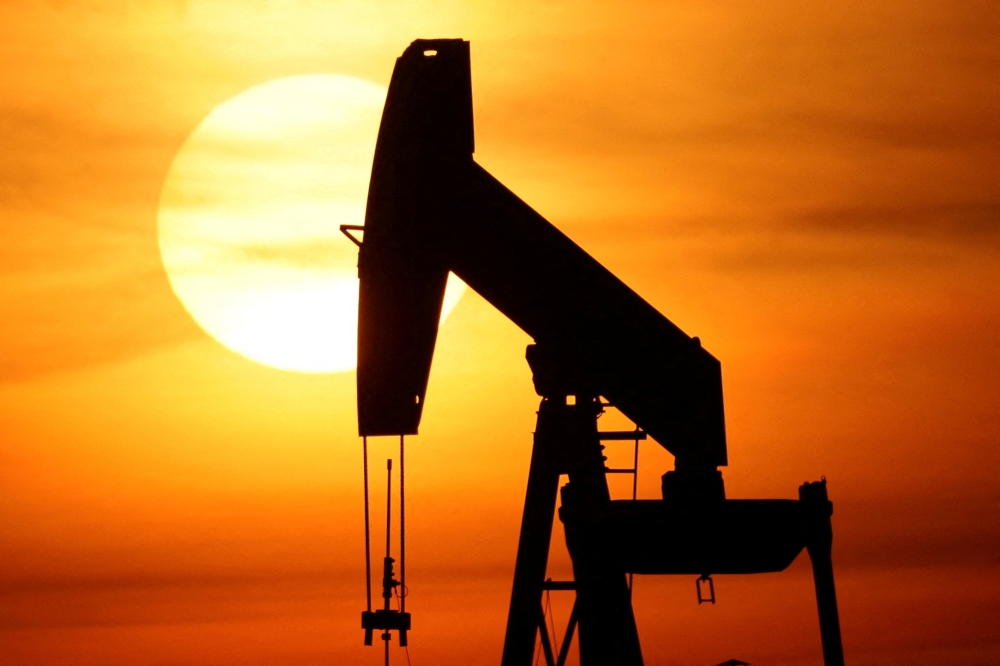 The sun sets behind an oil pump-jack outside Sommesous