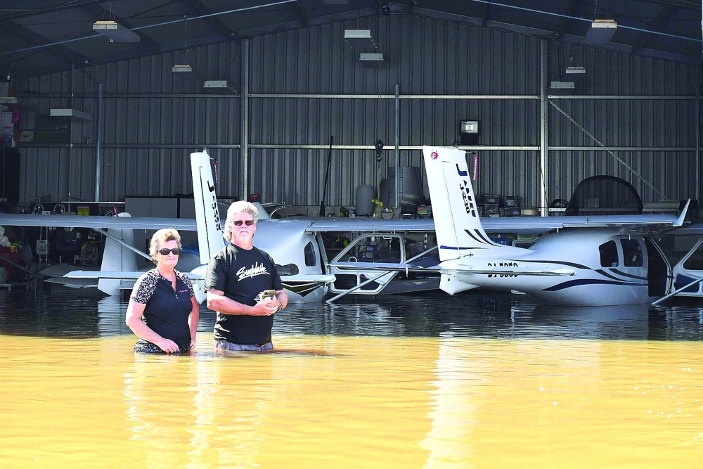 Flying instructor Peter Clement and his wife Kerrie stand in waist-high water as they examine their aircraft inside a hanger after a flood inundated Grafton Air Strip in Grafton. - AFP

