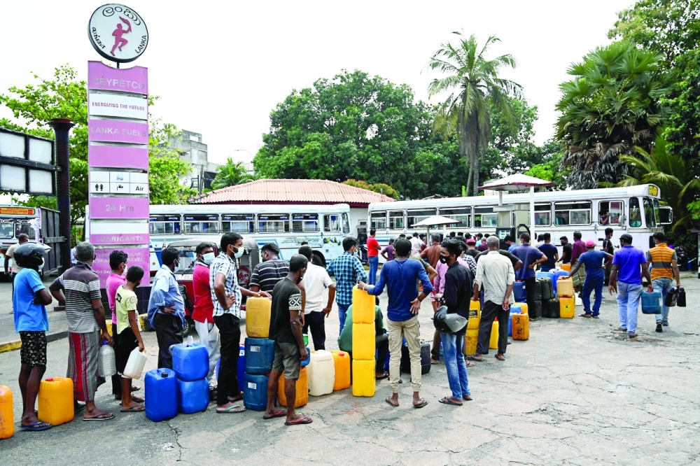 People stand in a queue to buy diesel fuel at a petrol station in Colombo. -- AFP
