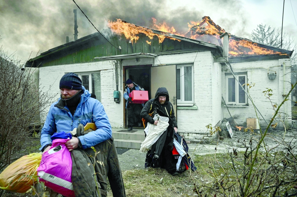 People remove personal belongings from a burning house after being shelled in the city of Irpin, outside Kyiv on Friday. -- AFP