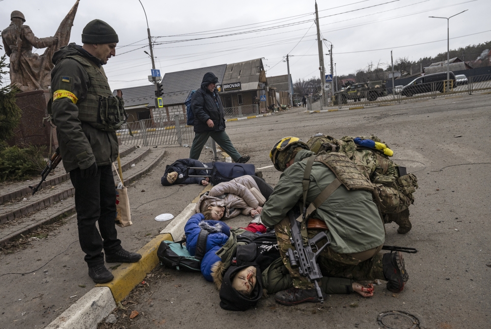Ukrainian soldiers try to save the father of a family of four  the only one at that moment who still had a pulse  moments after being hit by a mortar while trying to flee Irpin, near Kyiv, Ukraine, on Sunday, March 6, 2022. (Lynsey Addario/The New York Times)