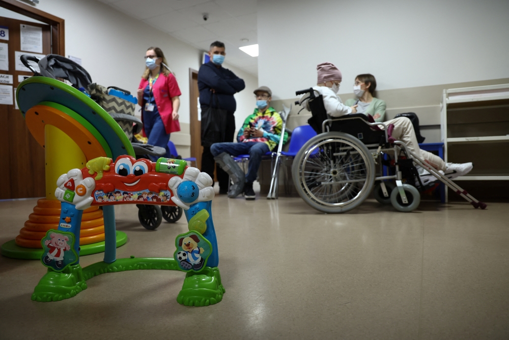 People wait outside the examination room of children's oncology ward at the Institute of Mother and Child hospital, in Warsaw