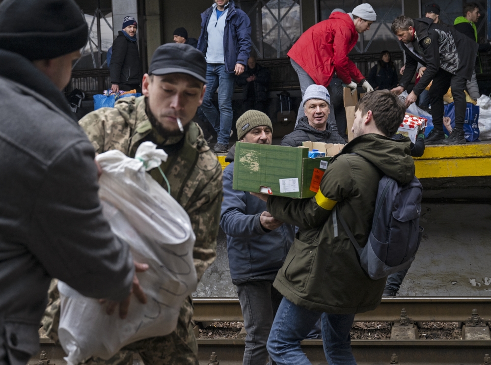 Volunteers load food and other aid which arrived by train from western Ukraine into vans, to be distributed to those in need across Kyiv, Ukraine, on Saturday, March 5, 2022. (Lynsey Addario/The New York Times)