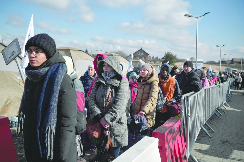 Ukrainians wait to board buses after crossing the border into Poland, at Medyka borders crossing. -- AFP