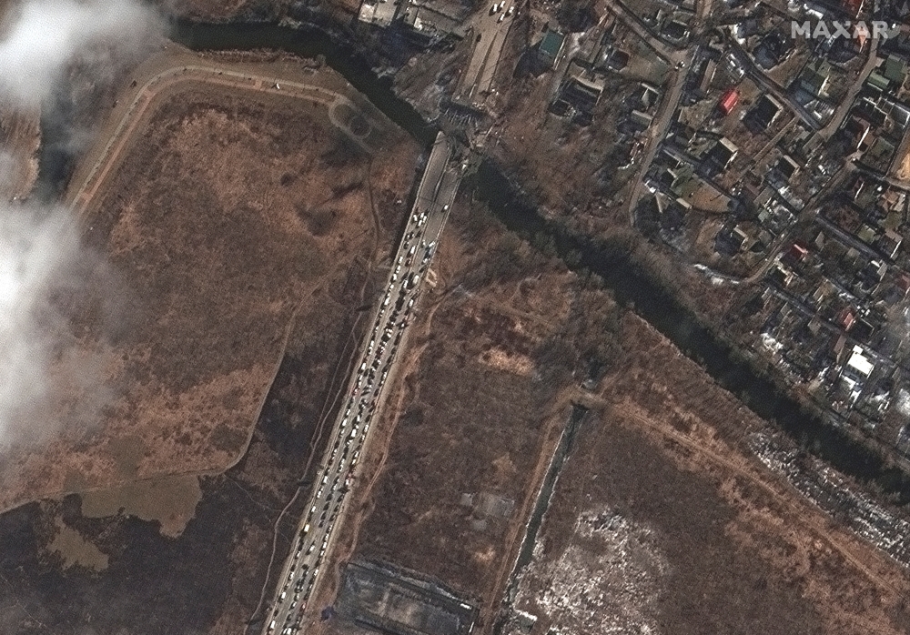Satellite imagery shows people and cars waiting by Irpin river bridge