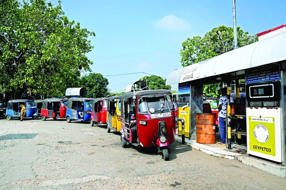 Drivers along with their auto rickshaws stand in a queue as they wait to fill petrol at a fuel station in Colombo on Friday. — AFP