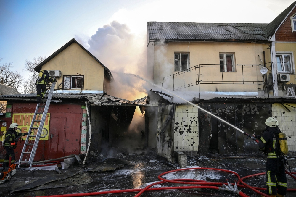 Firefighters extinguish a fire on a house after shelling in Kyiv on March 12, 2022. 