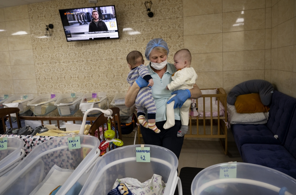 A nanny helps care a group of 19 babies born to Ukrainian surrogate mothers, now sheltered during the Russian invasion at a basement nursery in Kyiv, March 11, 2022. (Lynsey Addario/The New York Times)
