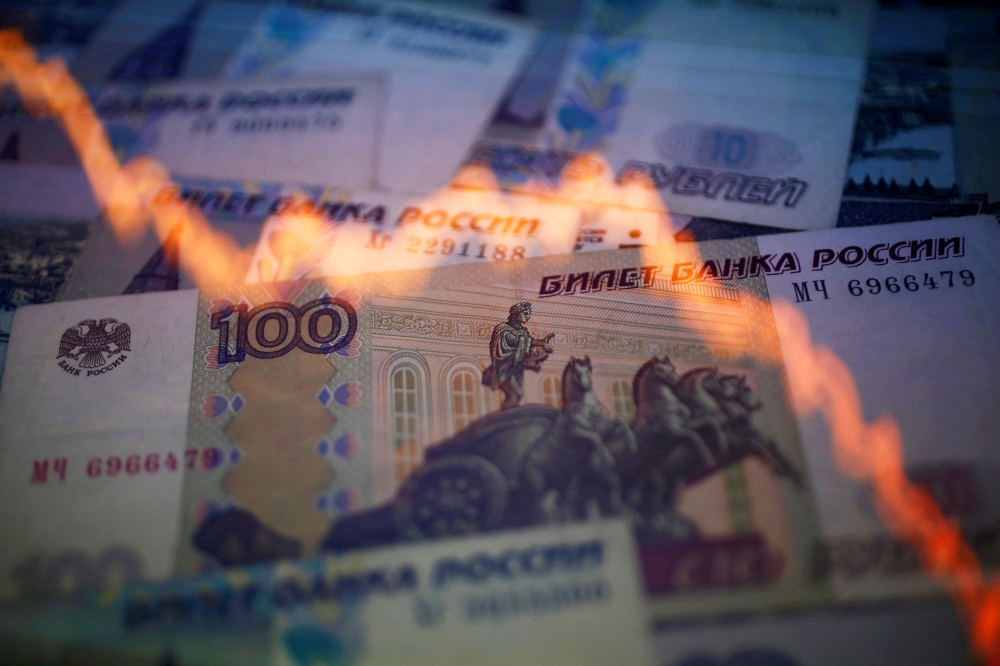 A reflection of a yearly chart of US dollars and Russian roubles are seen on rouble notes in this photo illustration.  — Reuters
