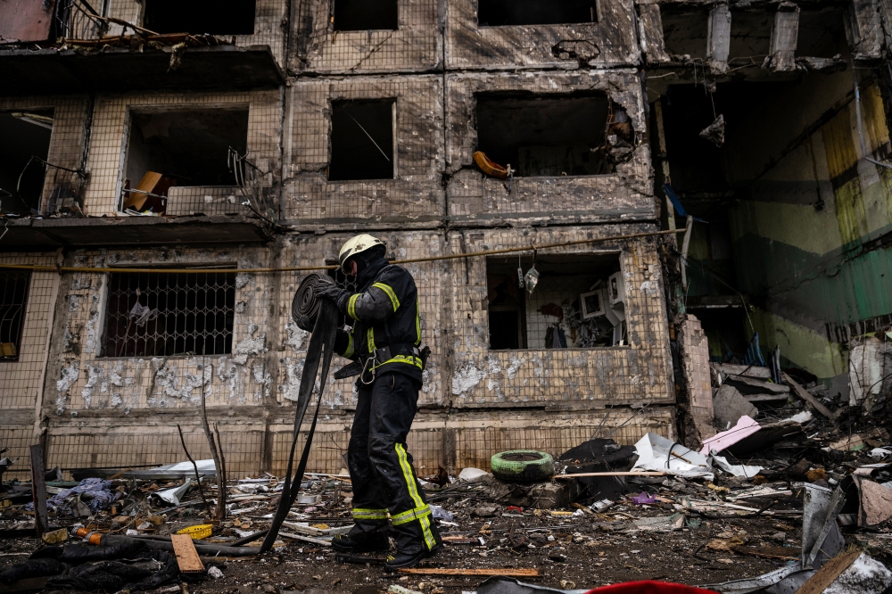 Emergency workers extinguish flames and help residents after their apartment building in the Obolon district of Kyiv, Ukraine, was struck by artillery shells on Monday, March 14, 2022. (Lynsey Addario/The New York Times) 