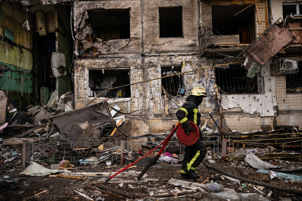 Emergency workers extinguish flames and help residents after their apartment building in the Obolon district of Kyiv, Ukraine, was struck by artillery shells on Monday, March 14, 2022. (Lynsey Addario/The New York Times) 