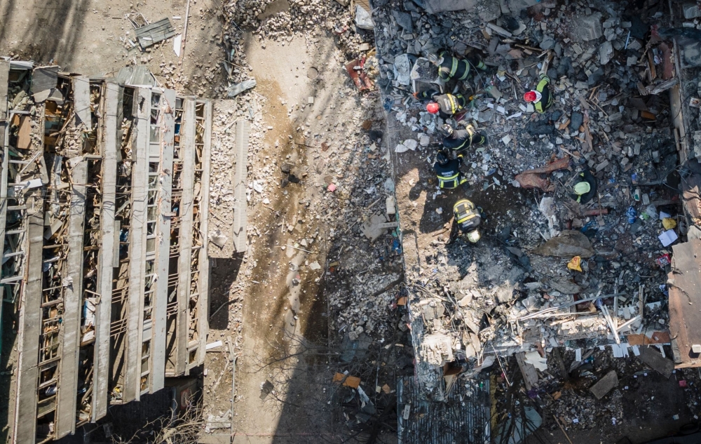An aerial view shows firemen working in the rubble of a residential building which was hit by the debris from a downed rocket in Kyiv on March 17, 2022. 