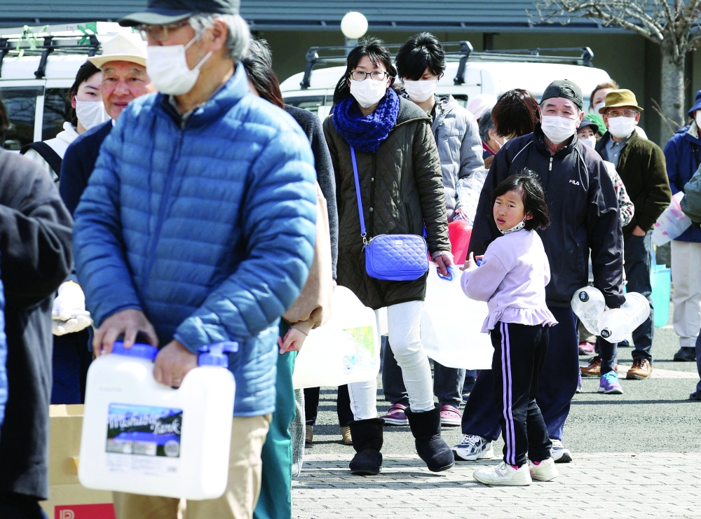 People wait in line to receive water following a strong earthquake in Kunimi. -- Reuters