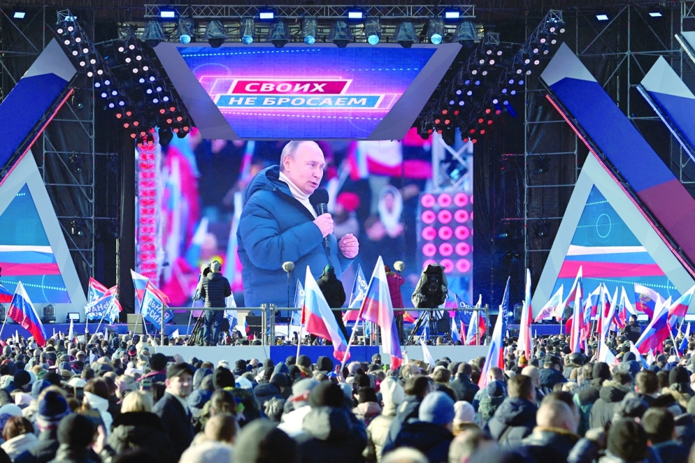 People watch a broadcast of Russian President Vladimir Putin's speech during a concert marking the eighth anniversary of Russia's annexation of Crimea outside Luzhniki Stadium in Moscow on Friday. -- Reuters