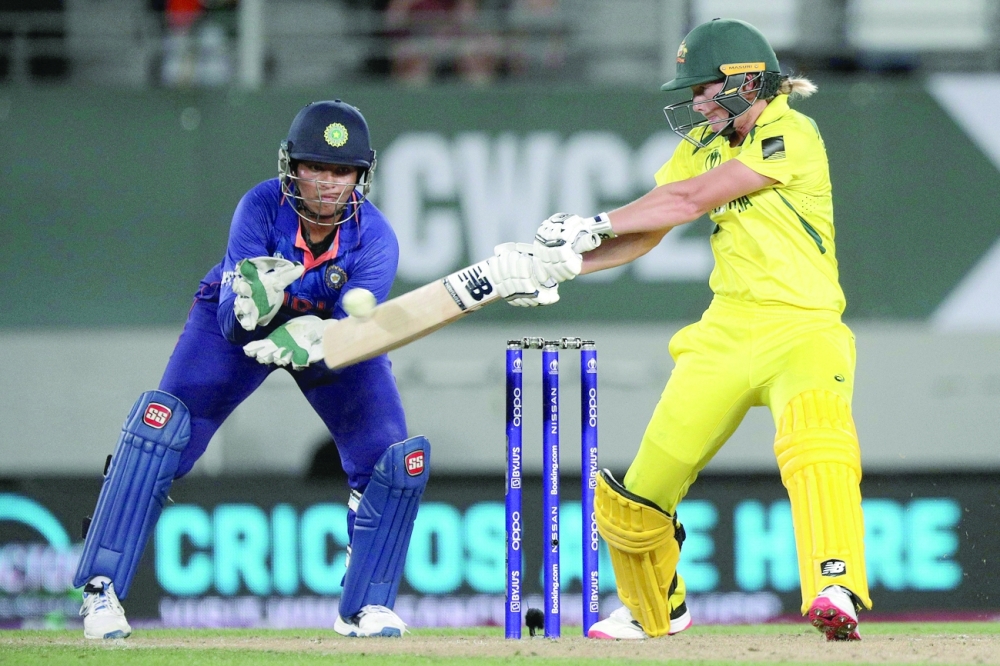 Australia's captain Meg Lanning plays a shot watched by India's wicketkeeper Richa Ghosh during the 2022 Women's Cricket World Cup match against India in Auckland. -- AFP