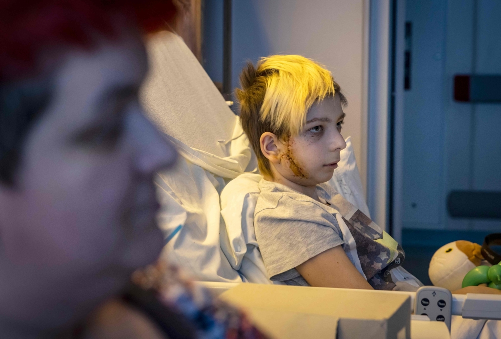 
Volodymyr, 13-years-old, sits in a hospital bed after being injured, in Kyiv on March 19, 2022. His family's car was caught in gunfire between Russian and Ukranian troops in Kyiv, on February 26. His father was killed and his mother was injured.

