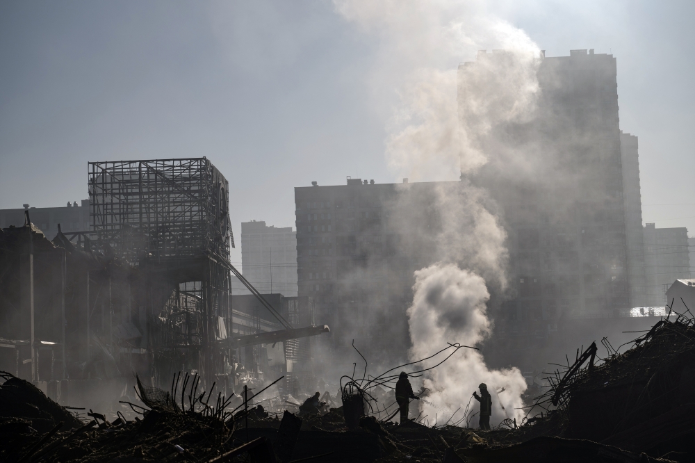 Firefighters and rescue workers on the scene after a Russian missile strike reduced a sprawling shopping mall in Kyiv to a smoldering ruin on Monday, March 21, 2022. (Lynsey Addario/The New York Times)