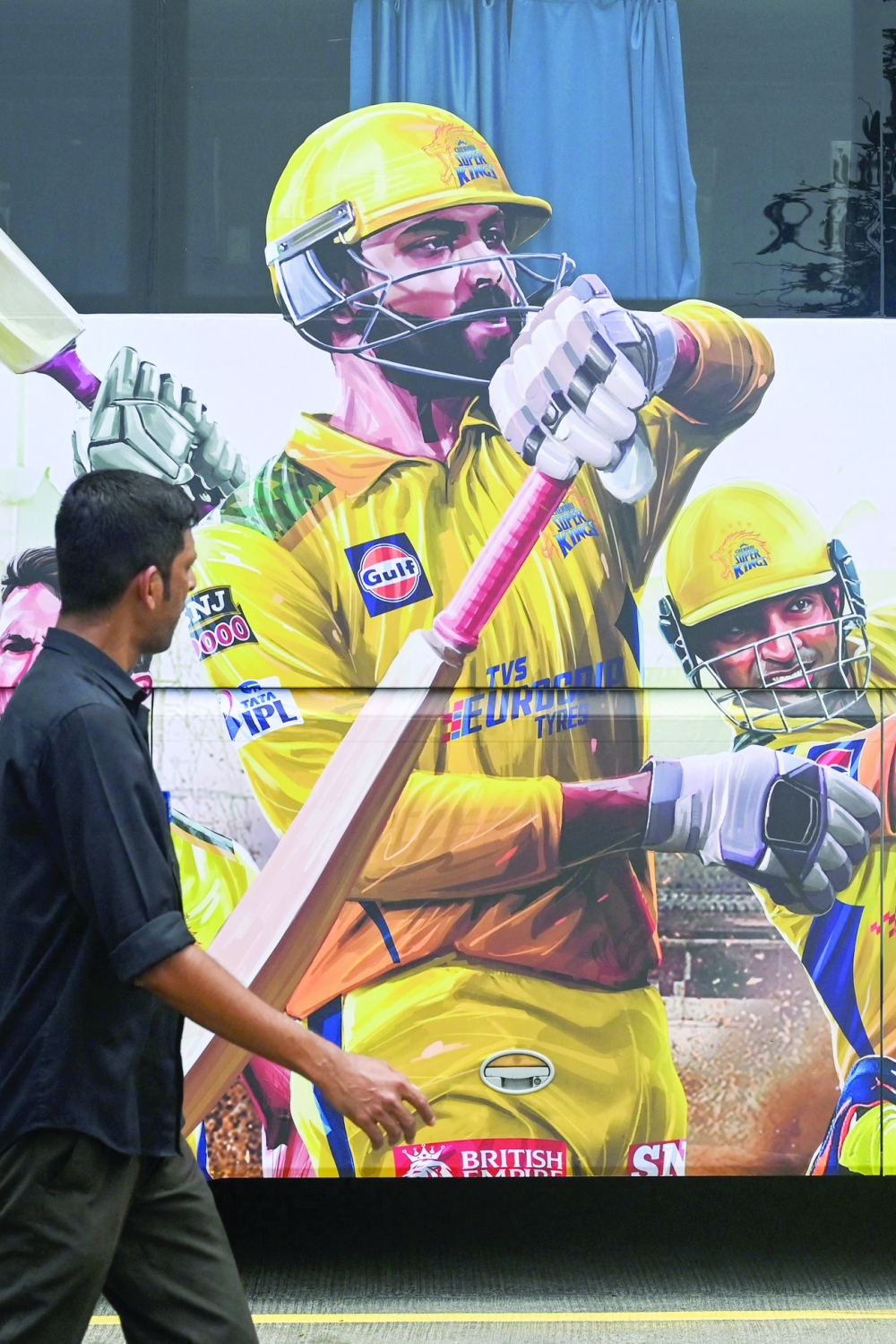 A pedestrian walks past an image depicting India's Ravindra Jadeja (C), who would be the new captain of Chennai Super Kings taking over the mantle from Mahendra Singh Dhoni. -- AFP