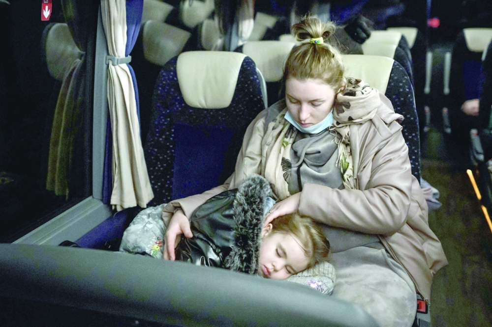 A Ukrainian refugee and a child are seen in a bus after landing at Zurich Airport from Krakow. -- AFP