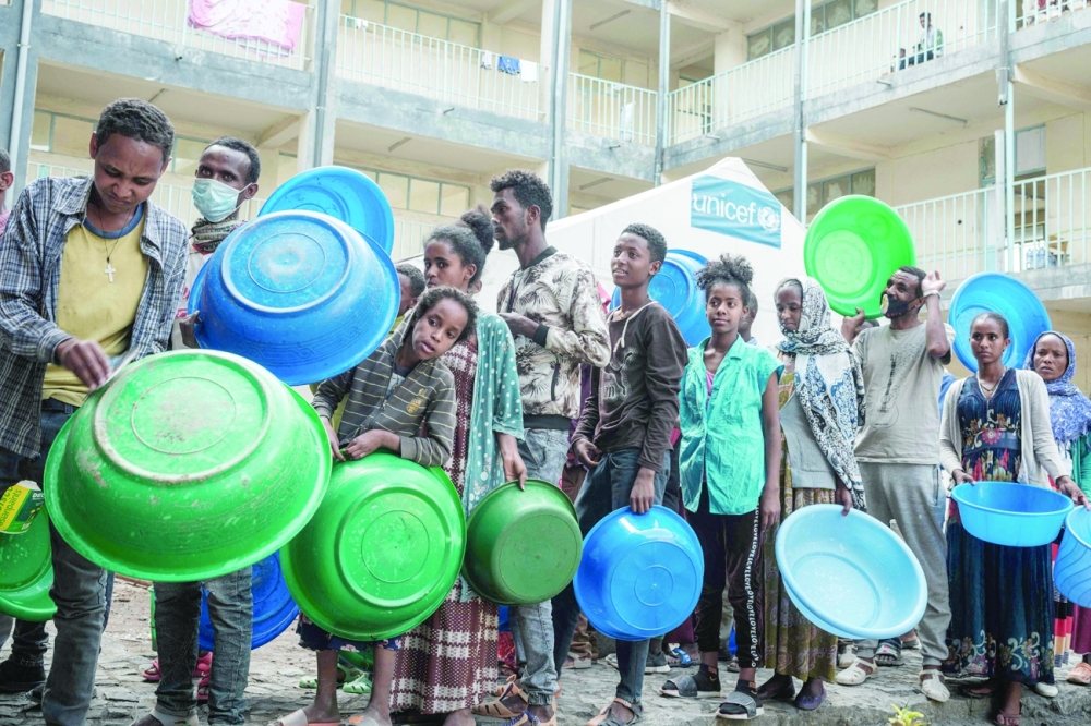 People who fled the violence in Tigray region wait to receive injeras, Ethiopia's staple food of sour fermented flatbread, at May Weyni secondary school, hosting 10,500 displaced as an IDP camp, in Mekele. -- AFP