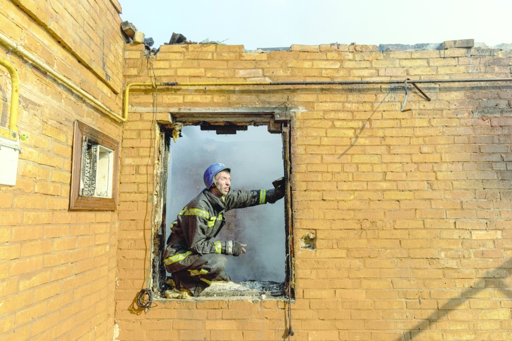 A firefighter works at a residential district that was damaged by Russia's shelling in Kyiv on Thursday. — Reuters