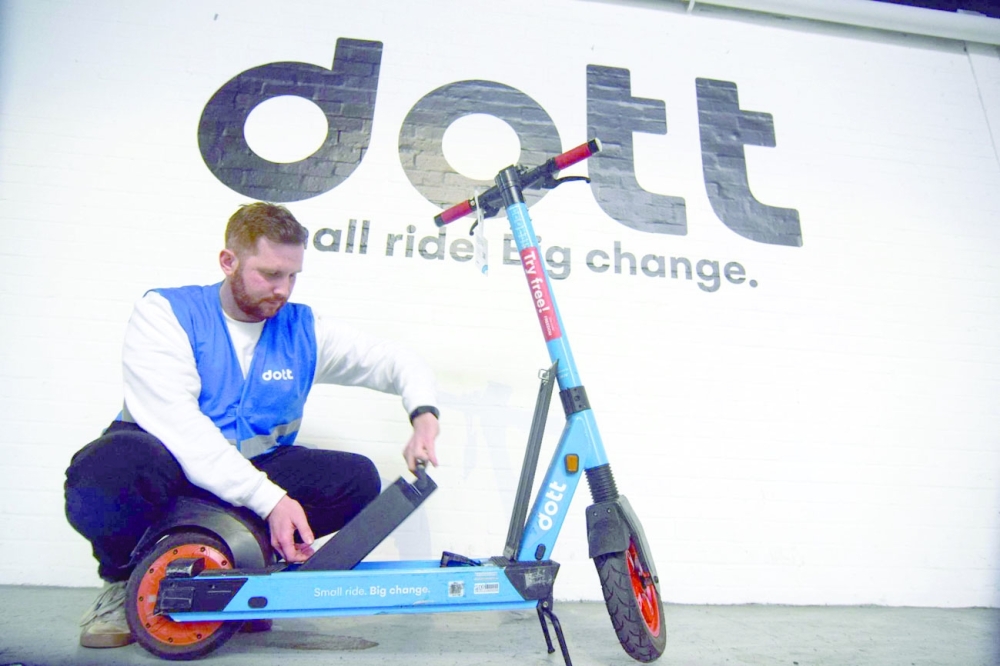 Ben Gillan, a warehouse operations manager at Dott, changes a swappable battery in one of the micromobility provider's electric scooters, in London.