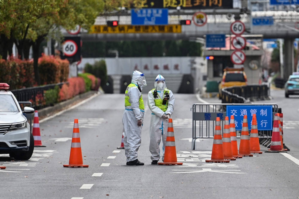 Police officers wearing protective gear control access to a tunnel in the direction of Pudong district in lockdown as a measure against the Covid-19 coronavirus, in Shanghai on March 28, 2022. 