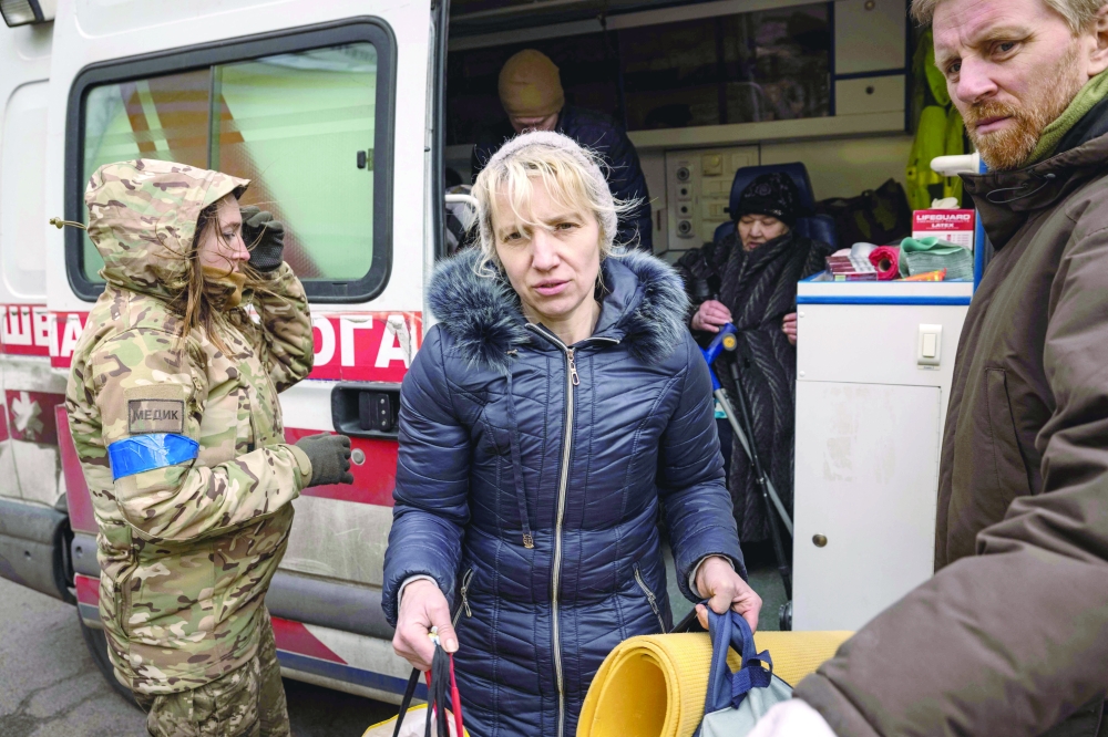 A woman is helped out of an ambulance after fleeing her home in the Kyiv suburb of Stoyanka. - AFP