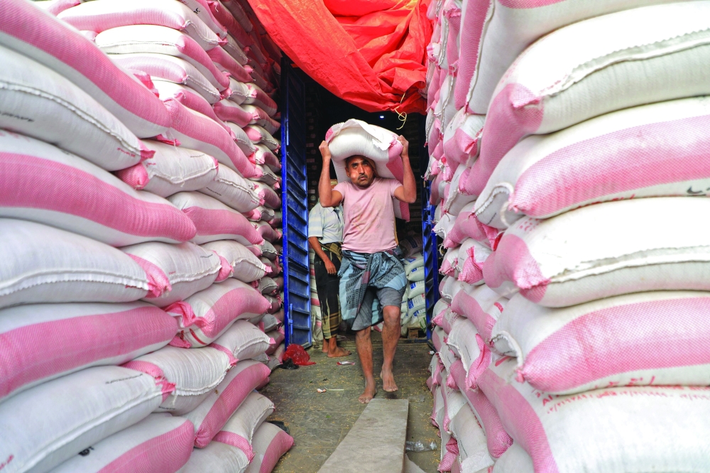 Yemeni workers carry bags of flour at a bakery in Sanaa. - AFP 