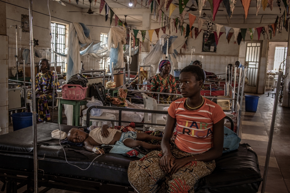 Fudia Kamara, 25, sits with her son Kabba Kargbo, 3, in the hospital in Kamakwie, Sierra Leone, on Feb. 15, 2022. Like nearly all the children in the pediatric ward, he had malaria. (Finbarr O'Reilly/The New York Times)
