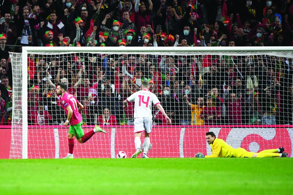 Portugal's midfielder Bruno Fernandes (L) celebrates scoring his team's first goal during the World Cup 2022 qualifying final first leg football match between Portugal and North Macedonia at the Dragao stadium in Porto on March 29, 2022.  (Photo by MIGUEL RIOPA / AFP)

