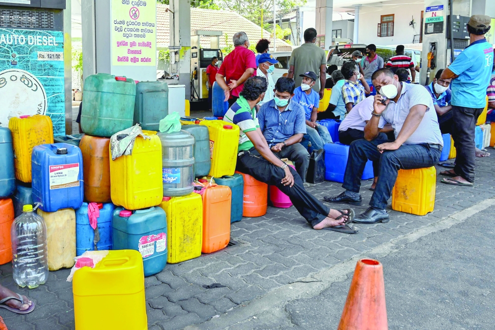 People wait in a queue to buy diesel at a fuel station in Colombo. -- AFP