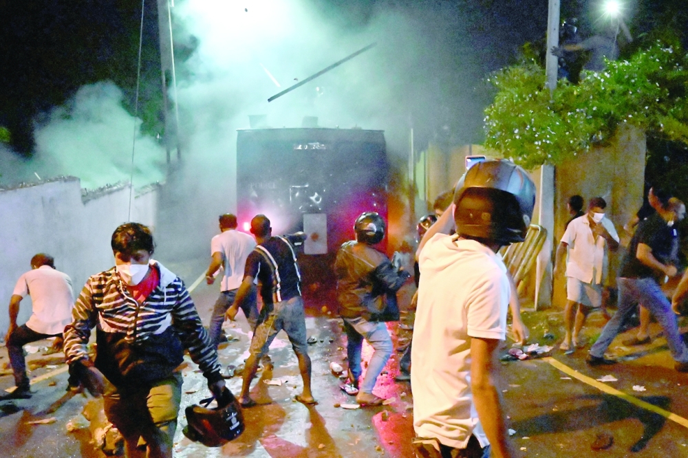 People clash with riot police as they demonstrate outside the president's home in Colombo. -- AFP