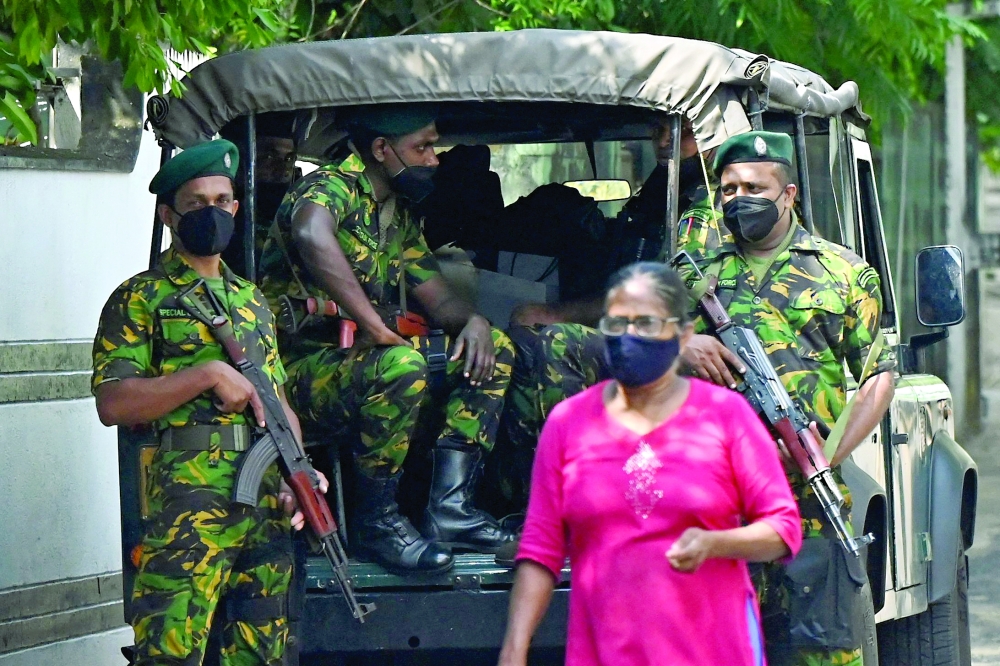 A pedestrian walks past Special Task Force (STF) personnel standing on guard along a street in Colombo. - AFP