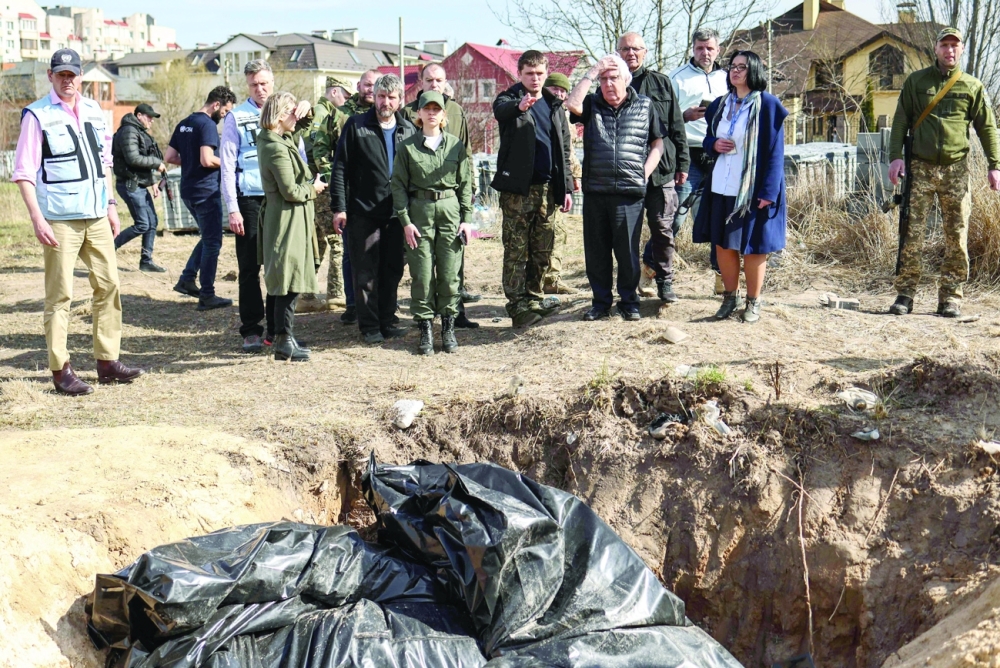 UN humanitarian chief Martin Griffiths (5th R) reacts at the site of a mass grave that Ukrainians had dug near a church on Thursday during his three-hour visit in Bucha, a day after he visited Moscow. - AFP