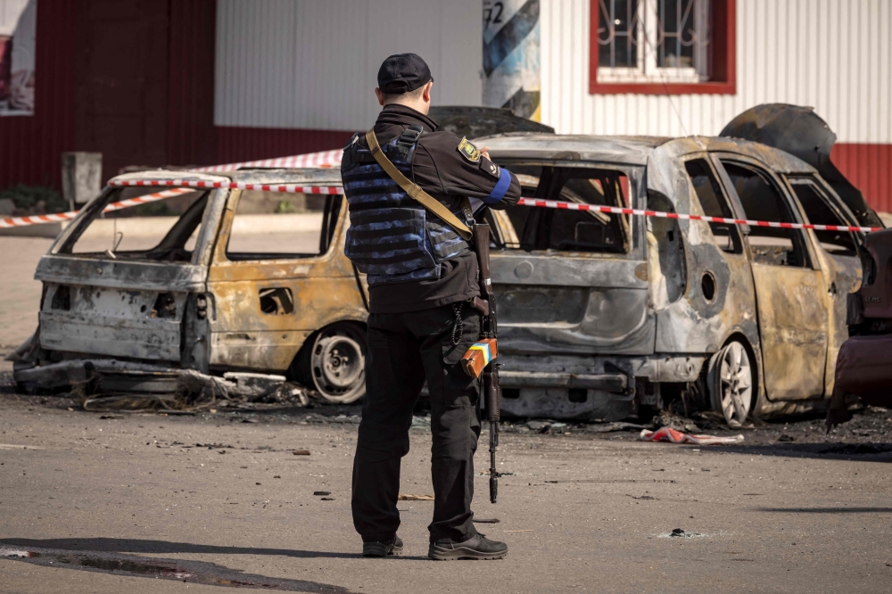 A Ukrainian police stands by calcinated cars outside a train station in Kramatorsk, eastern Ukraine, that was being used for civilian evacuations, after it was hit by a rocket attack killing at least 35 people, on April 8, 2022.
