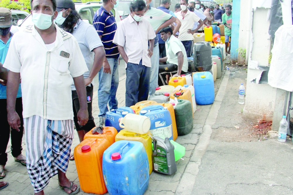 People wait in a queue to buy diesel at a Ceylon Petroleum Corporation fuel station in Colombo on April 9, 2022. The shortages of essentials have been caused by a wide-ranging import ban as Sri Lanka seeks to conserve its meagre foreign currency reserves to pay its debts. (Photo by AFP)