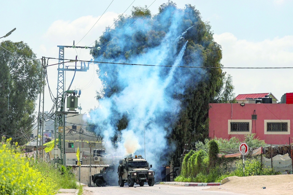 Tear gas canisters are fired from an Israeli military vehicle near the Palestinian refugee camp of Jenin in the occupied West Bank on Saturday. - AFP