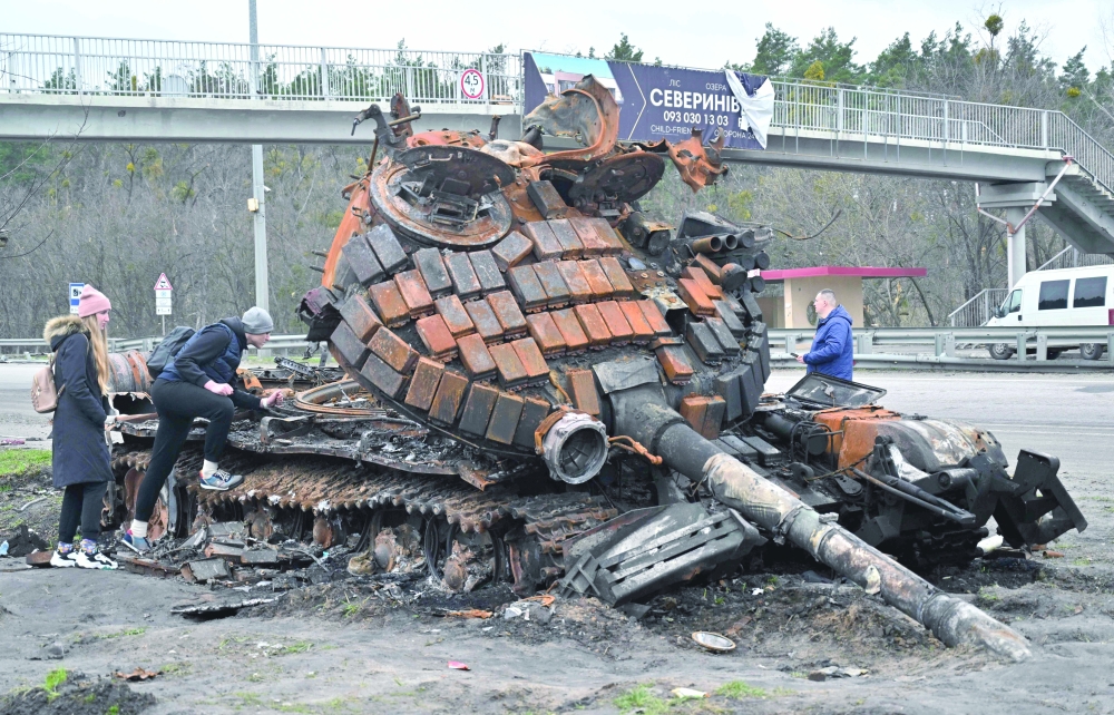 Residents look at a destroyed Russian tank outskirts of Buzova village, west of Kyiv. - AFP

