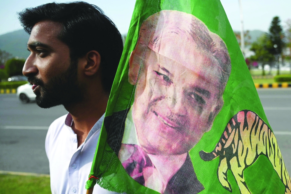 A PML-N supporter holds a party flag with an image of Shehbaz Sharif outside the parliament house building in Islamabad. - AFP