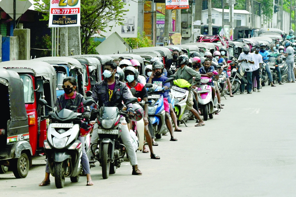 Motorbikes and three-wheeler vehicles queue at a Ceylon Petroleum Corporation fuel station in Colombo. - AFP
