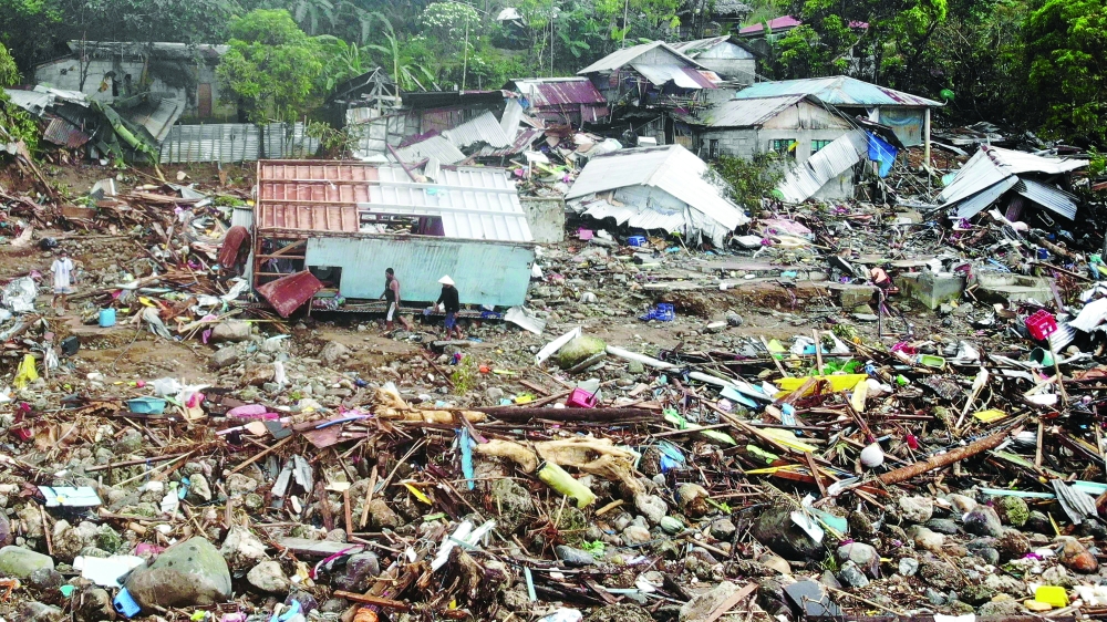 An aerial view shows residents walking past destroyed houses in the village of Pilar, Abuyog town, Leyte province after a landslide struck the village due to heavy rains. - AFP

