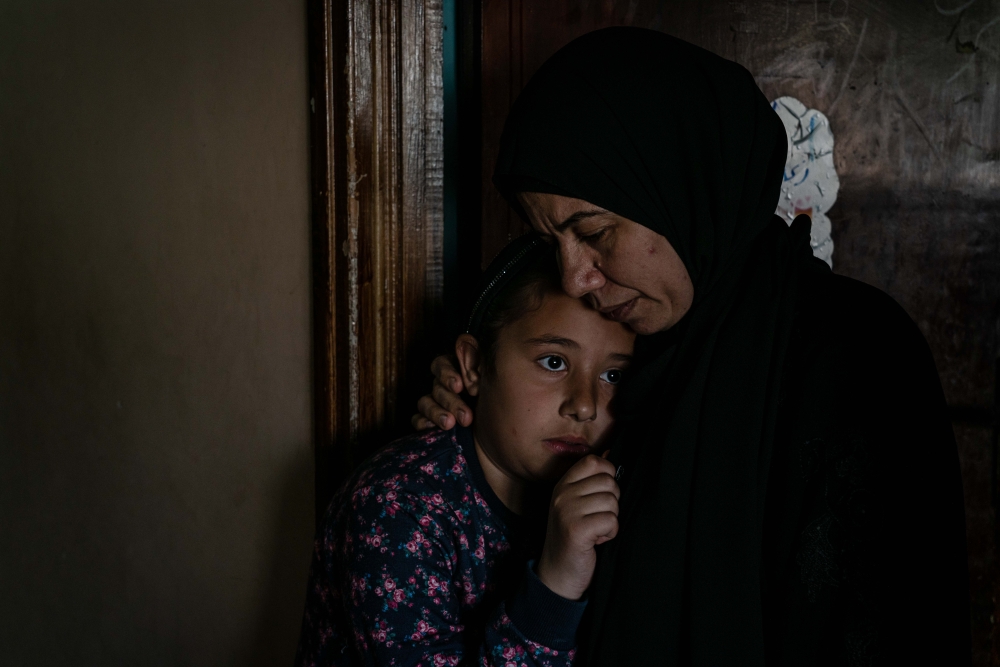 Khuloud Zakarna, whose son is among the 14 or more Palestinians killed by Israeli forces since the beginning of Ramadan, comforts her daughter Sedra at home in Jenin, in the West Bank, on April 15, 2022. (Samar Hazboun/The New York Times)