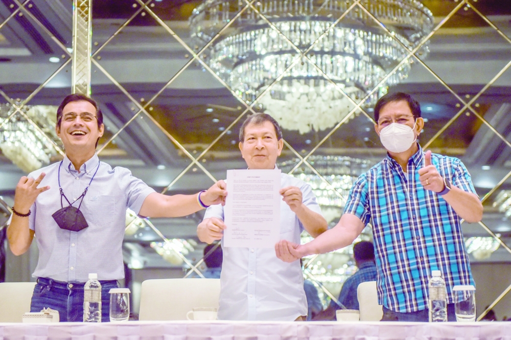 Philippine presidential candidates Manila City Mayor Domagoso, former defence secretary Gonzales, and senator Lacson show their joint statement during a press conference in Makati City. - AFP