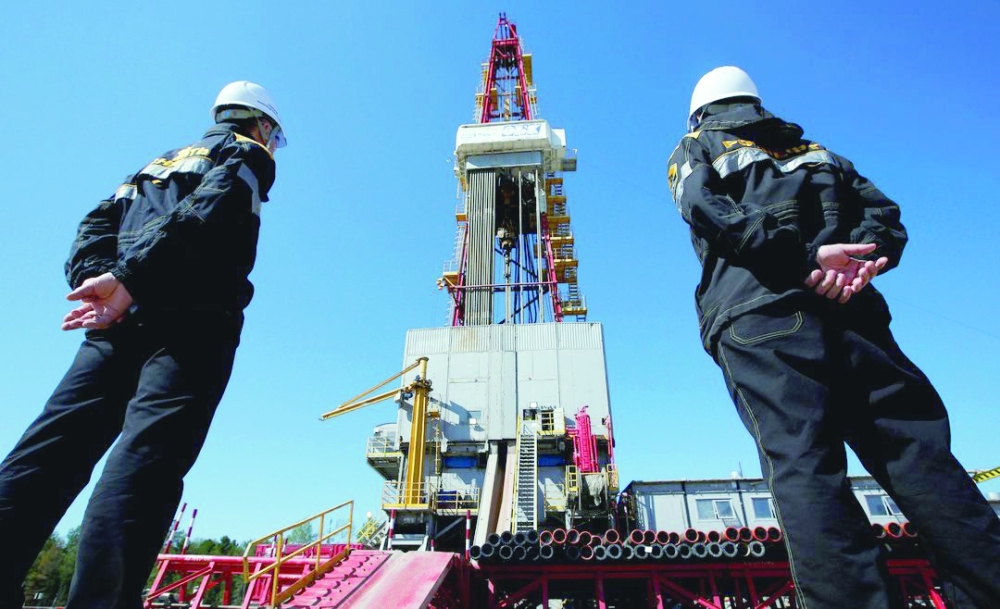 Workers look at a drilling rig at a well pad of the Rosneft-owned Prirazlomnoye oil field in Nefteyugansk, Russia. — Reuters