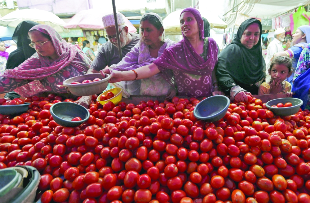 Local residents buy tomatoes from a roadside vegetable market in Ahmedabad, India. — Reuters
