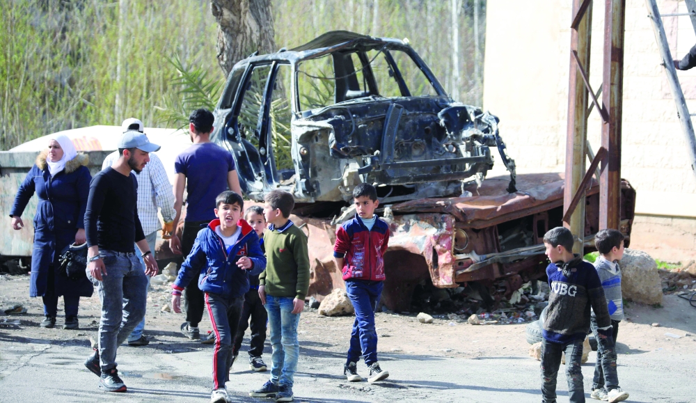 Children walk by a car during the filming of the Syrian Social series in the Wadi Barada suburb of Damascus. — AFP