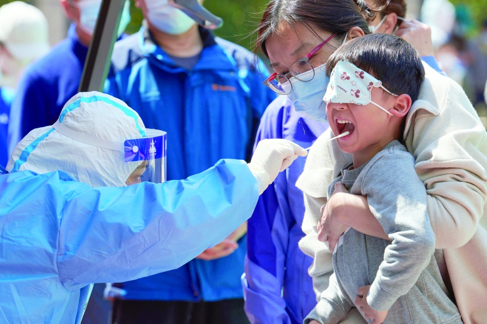 A child receives a swab test for the coronavirus during a Covid-19 lockdown in Pudong district in Shanghai. — AFP