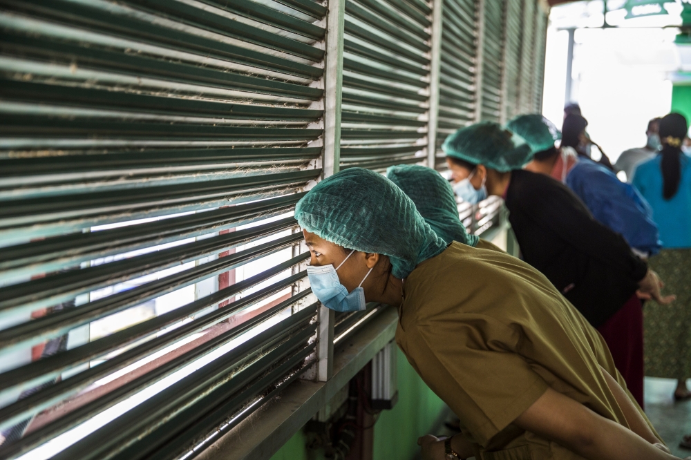 Medical staff watch from a hospital rooftop as security forces crack down on protestors in Mandalay, Myanmar, on Feb. 28, 2021.  (The New York Times)